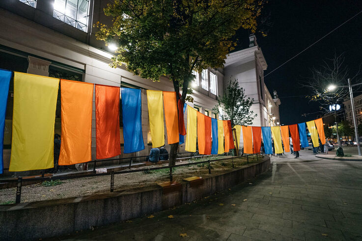 Ansicht des Obdach Josi bei Nacht mit aufgehängten Fahnen zum Jubiläum in den Farben gelb, orange und blau (Bild: Thomas Meyer Photography)