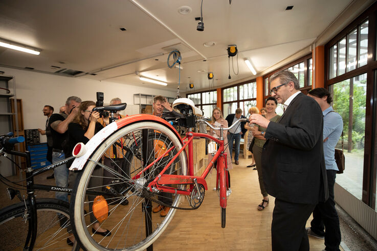 Peter Hacker sieht sich ein fertiges Fahrrad in der Bike Kitchen Favorita an und wird dabei von Pressefotografen fotografiert (Bild: PID/Ismael Gökmen )