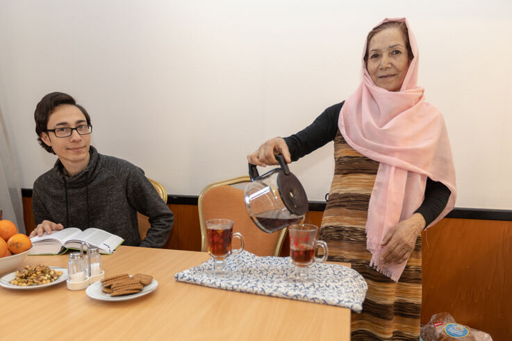 Ein Teil einer Flüchtlingsfamilie mit jüngerem Mann und älterer Frau mit Kopftuch die Tee in Gläser schenkt  sitzen bei Tisch in der Grundversorgung Obdach Favorita (Bild: FSW)