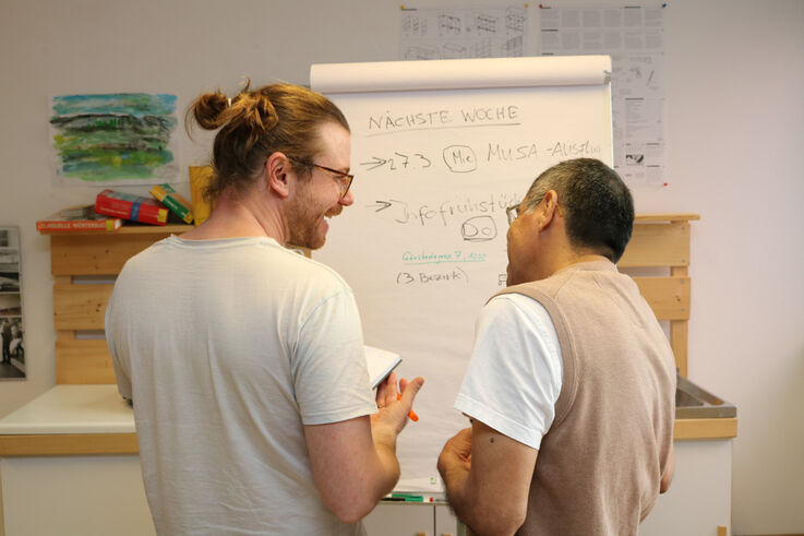 Zwei Teilnehmer bei einem Organisationstreffen von Forum Obdach Wien wie sie sich gegenseitig anlächeln und vor einer Flipchart stehen (Bild: FSW) Zwei Teilnehmer bei einem Organisationstreffen von Forum Obdach Wien wie sie sich gegenseitig anlächeln und vor einer Flipchart stehen (Bild: FSW)