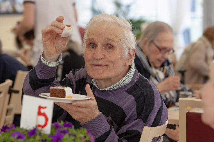 Tageszentrums-Besucher hält einen Teller mit einem Stück Geburtstagstorte in der Hand und lässt sich diese schmecken (Bild: FSW)